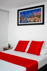 a white bed with red pillows in a bedroom at Hotel Los Angeles in Calarcá