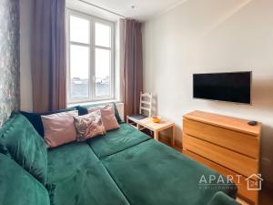 uma sala de estar com um sofá verde e uma televisão de ecrã plano em Biskupia Central Apartment em Gdansk