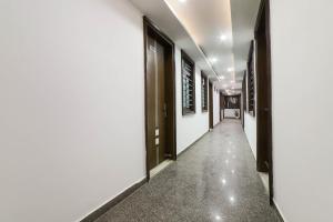um corredor com paredes brancas e portas pretas em Hotel Seven S em Nova Deli