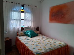 ein Schlafzimmer mit einem Bett, einem Fenster und einem Gemälde in der Unterkunft Aconchegante casa à beira da praia in Maricá