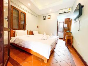 a bedroom with a bed with two cats sitting on it at khong kham Hotel in Luang Prabang