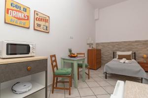 Dora's Apartments في لاغاناس: غرفة مع سرير وطاولة مع ميكروويف