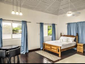 Round the point Bungalow في باستيمينتوس: غرفة نوم بسرير وطاولة وستائر زرقاء