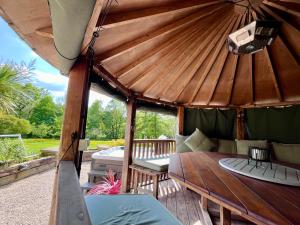 a large wooden gazebo with a bench and a table at Stillmeadow in Westwood
