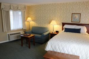 um quarto de hotel com uma cama e uma cadeira em The Village Inn em Harrisonburg