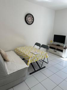a living room with a table and chairs and a clock at Appartement avec jardin - Le Citronnier in Menton
