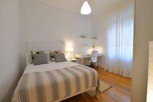- une chambre blanche avec un lit et un bureau dans l'établissement Apartamento en zona residencial cerca del Guggenheim, à Bilbao