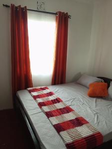 a bed in a bedroom with a window with red curtains at COZY COTTAGE® 