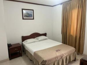 a bedroom with a bed and a table and a window at Hotel del Parque Davinchi in Calarcá