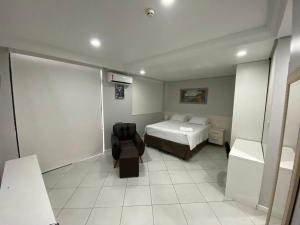een slaapkamer met een bed en een stoel erin bij Millenium Hotel Flat in Manaus