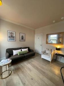 sala de estar con sofá negro y silla blanca en Bijou apartment in the heart of Melrose, en Melrose