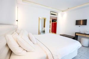 Dormitorio blanco con cama blanca y almohadas en Diamond Deluxe Hotel - Adults Only en Cos