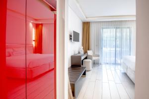 una camera d'albergo con letto rosso e scrivania di Diamond Deluxe Hotel - Adults Only a Città di Kos