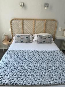 Cama con colcha y almohadas de estampado azul en Hôtel Eden - La Baigneuse, en Juan-les-Pins