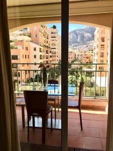 a dining room table with a view of a balcony at Monaco F1 Port de Fontvieille refined apartment overlooking the garden, with pool access, 10 min from GP in Monte Carlo