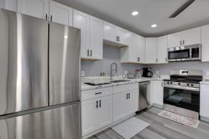 La cuisine est équipée de placards blancs et d'un réfrigérateur en acier inoxydable. dans l'établissement Pet-Friendly Phoenix Apartment 10 Mi to Downtown!, à Phoenix