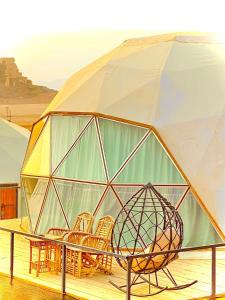 a glass dome with chairs and a table with an umbrella at Hasan Zawaideh Camp in Wadi Rum