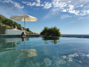 a woman sitting in a swimming pool with an umbrella at Casa Alquerque in Monsaraz