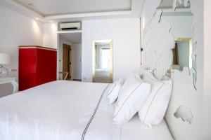 una camera da letto con un letto bianco con cuscini bianchi di Diamond Deluxe Hotel - Adults Only a Città di Kos