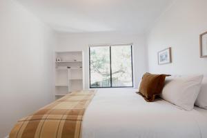 ein weißes Schlafzimmer mit einem großen Bett und einem Fenster in der Unterkunft Trendy apartment in the heart of West Hobart in Hobart