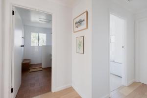 einen Flur mit weißen Wänden und ein Badezimmer mit einem Spiegel in der Unterkunft Trendy apartment in the heart of West Hobart in Hobart + 56 Fotos