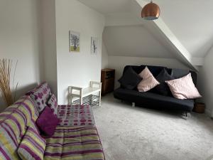 sala de estar con sofá negro y almohadas moradas en King’s Road Apartments, en Harrogate