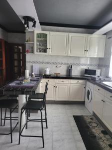 a kitchen with white cabinets and a table and chairs at Casa da Palmeira in Velas