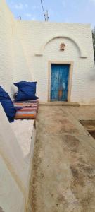 a bed with blue pillows sitting in front of a building at Typique appartement in Houmt Souk