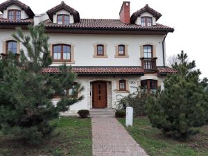 een groot wit huis met bomen ervoor bij Dom przy stoku 2 in Bałtów