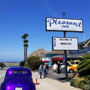 un coche púrpura estacionado en una acera junto a una señal en Pleasant Inn, en Morro Bay