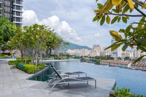 a swimming pool with a chair and a bench in a city at Tatami with Seaview, 9pax, Urban Suites by PG Home in George Town
