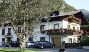 a large house with cars parked in front of it at Gästehaus Riki Oberschmid in Steinbach am Attersee