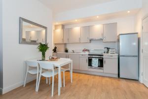 una cocina con armarios blancos y una mesa y sillas blancas. en King’s Road Apartments, en Harrogate