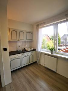 a kitchen with white cabinets and a large window at Seeromantik in Amelinghausen