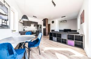 a kitchen and dining room with a table and blue chairs at Apartament Belvedere Ławica Airport in Poznań
