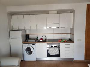 a kitchen with white cabinets and a washing machine at Apartamento con vistas al mar y montaña in El Verger
