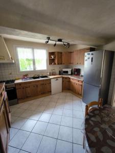 a kitchen with wooden cabinets and a refrigerator at Ma Maison de Campagne in Le Brusquet