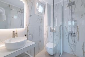 a white bathroom with a sink and a shower at Chloe Studios in Parga
