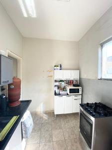 a small kitchen with a stove and a refrigerator at Quarto de Solteiro Uberaba in Uberaba