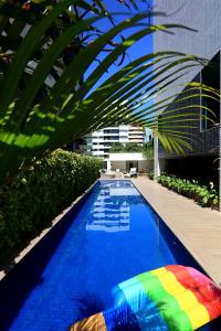 uma piscina com um guarda-sol colorido ao lado de um edifício em Porto Kaeté Hotel em Maceió