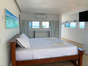 a bedroom with a bed with white sheets at Flats e Suítes Elcaline in Porto De Galinhas