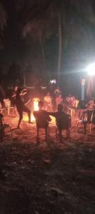 Un groupe de personnes debout autour d'un feu la nuit dans l'établissement Victoria's River View Resort, à Pondichéry