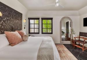 a bedroom with a large white bed and a mirror at Lucille Palm Springs in Palm Springs