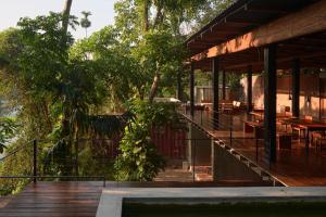 Yatiyantota的住宿－River Pavilion, Kitulgala，一座带甲板、桌子和树木的建筑