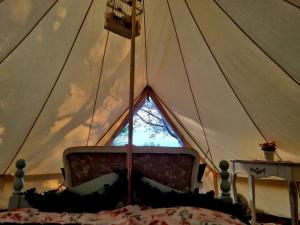 - une chambre dans une tente avec un lit et une fenêtre dans l'établissement French Tent secret garden glamping, à Newark-on-Trent