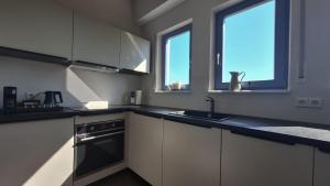 a kitchen with white cabinets and a sink and two windows at KELLER APARTMENT l 30 in Sulz am Neckar