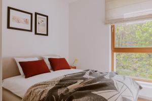 um quarto com uma cama com almofadas vermelhas e uma janela em Forest Zen Sopot z widokiem na morze - Praia Apartments - Polsat Plus Arena em Sopot