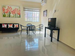 uma sala de estar com uma televisão e uma mesa e cadeiras em Orquideas Villas & Studios at Country House em Cancún