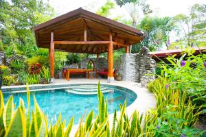 - une piscine avec un pavillon en bois à côté d'un jardin dans l'établissement Casitas Del Rio Riverfront Jungle Beach Vacation, à Uvita