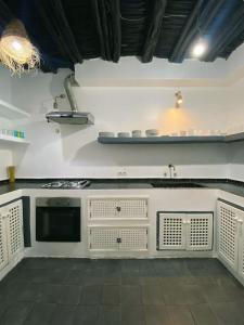 a kitchen with white cabinets and a stove top oven at Riad Dar alma in Essaouira +28 photos